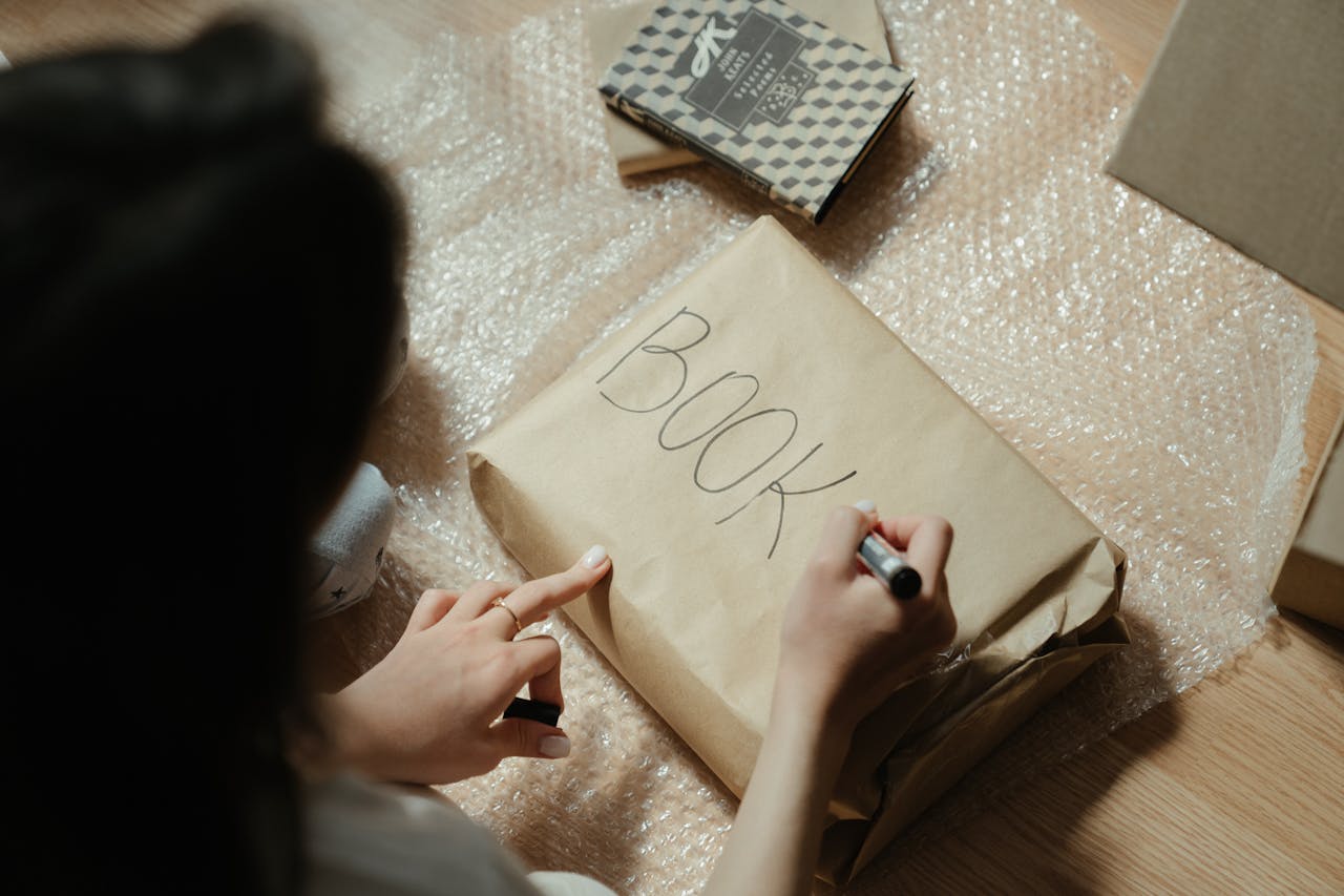 gallery-01 Close-up of a person wrapping books in bubble wrap and kraft paper for safe shipping.