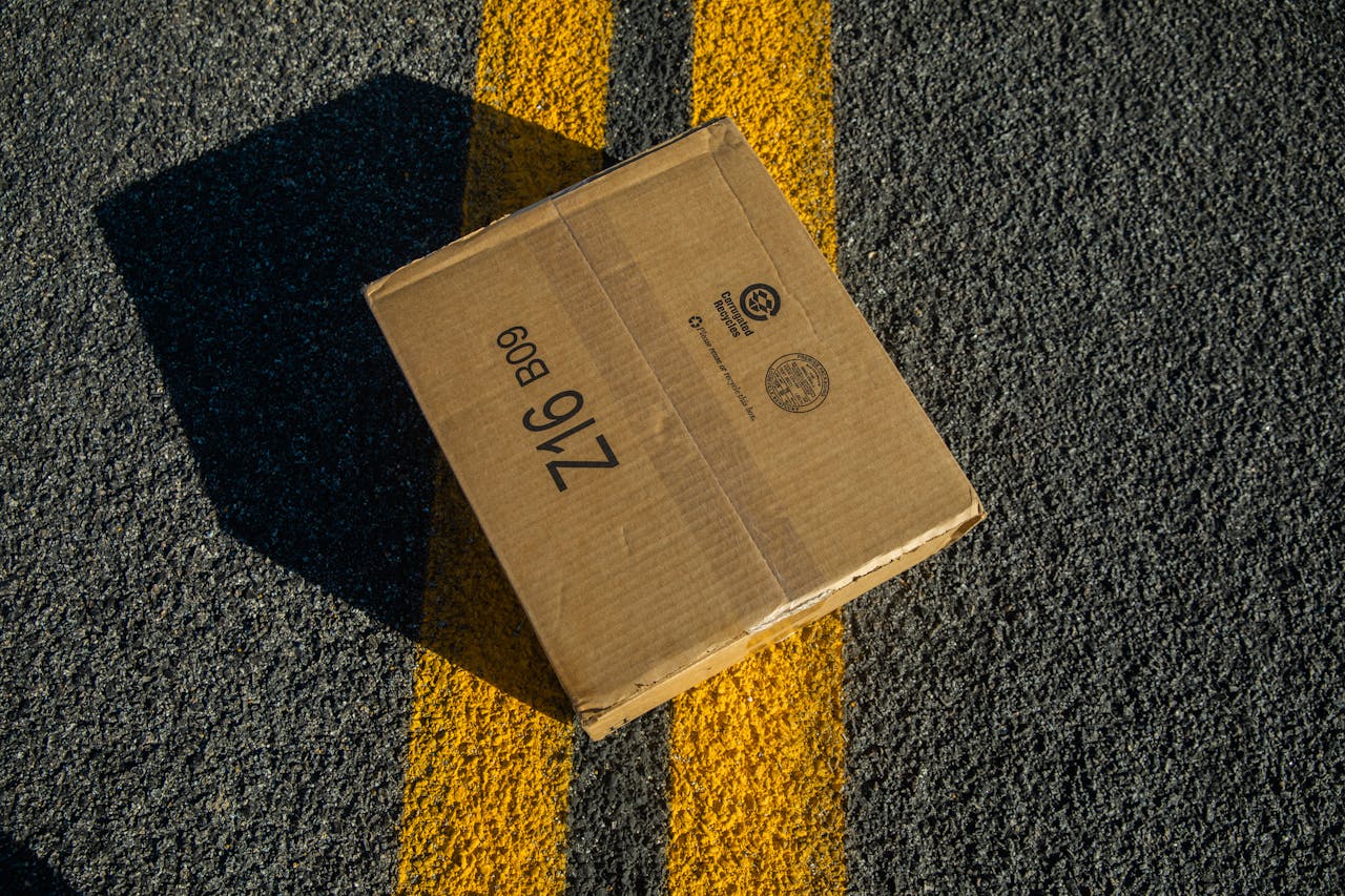 gallery-02 A cardboard box on road asphalt marked with yellow lines, captured in a unique angle.